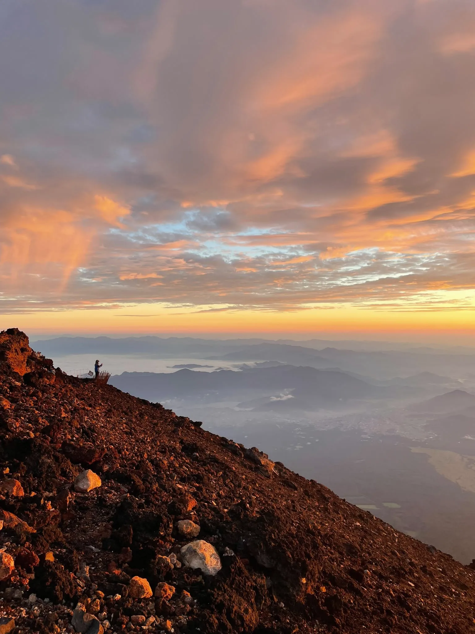 A walker watching the morning light from a rocky mountain slope