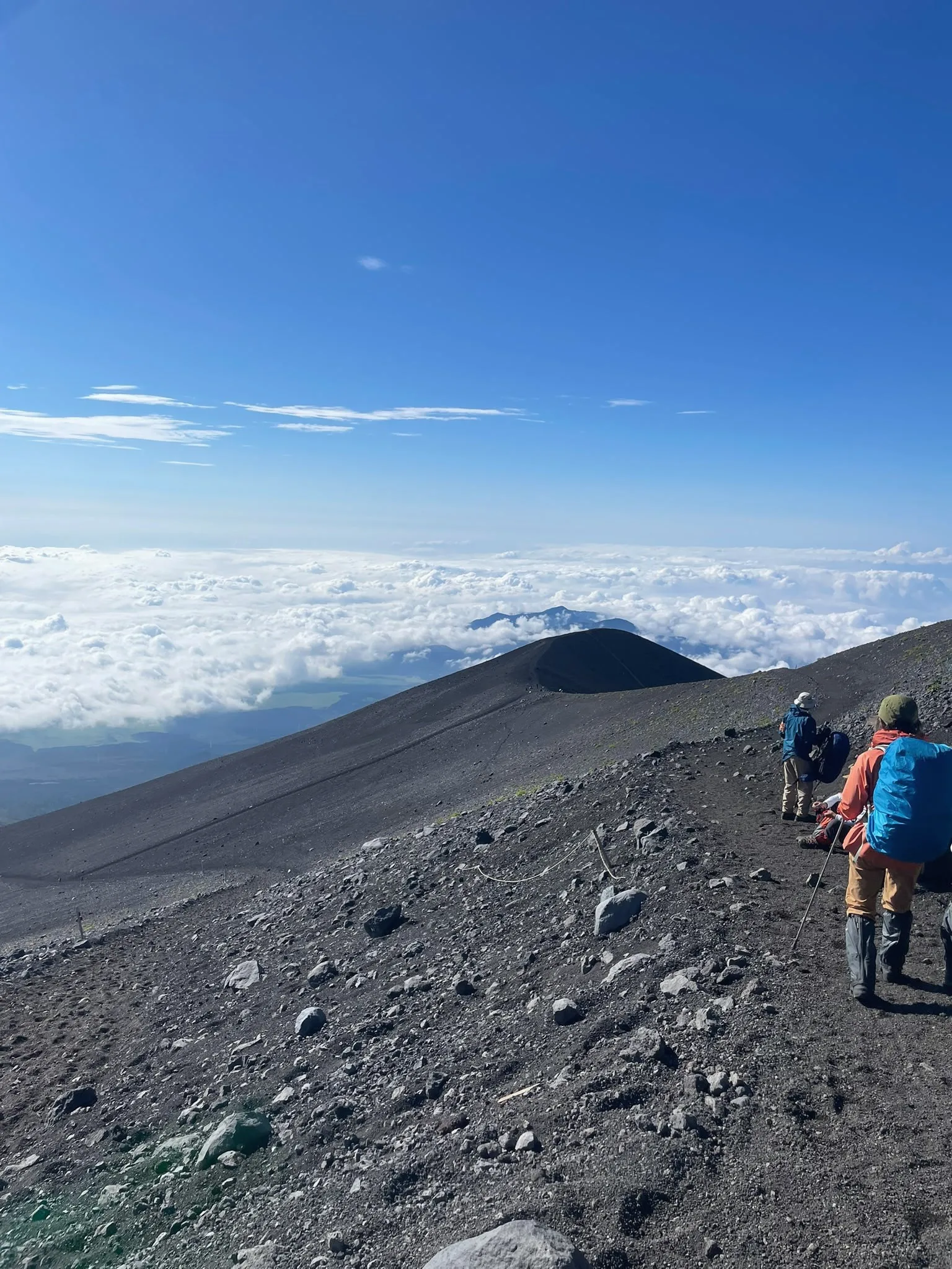 Hikers following a volcanic mountain trail above the clouds